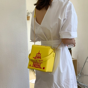 Detailed view of yellow take-out box style crossbody bag with red tower print and chain