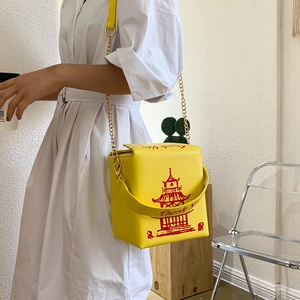 Detail of yellow Chinese takeout box crossbody bag with red print and chain strap