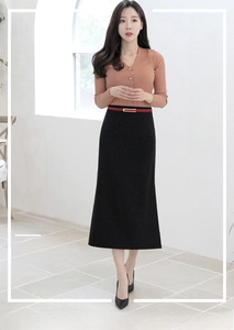 Détail de la fine ceinture en cuir rouge avec boucle dorée sur une robe noire femme