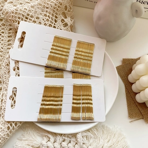 Detailed view of glossy golden bobby pins arranged on display cards for hairstyling