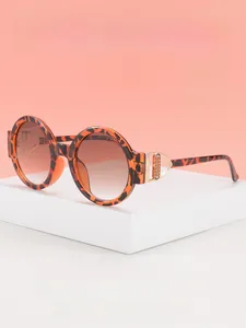 Close-up of leopard print round sunglasses featuring hollow golden metal hinge details