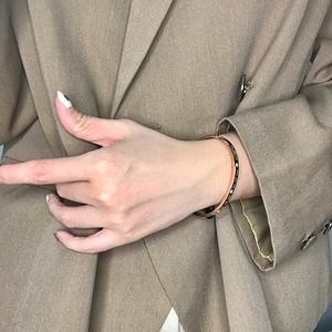 Eleganter Armreif in Roségold mit römischen Ziffern, getragen zu einem schicken Outfit