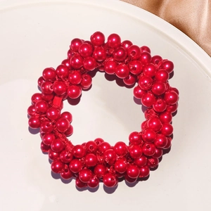 Macro shot of elegant red faux pearl beaded hair tie on a white ceramic plate tray