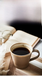 Close-up of retro ceramic coffee cup with textured brown glaze and white ribbed interior