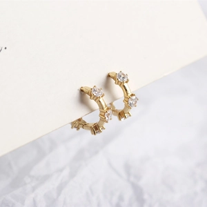 Macro shot of gold S925 sterling silver huggie earrings with three sparkling zircons