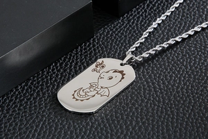 Detail of silver stainless steel dog tag pendant featuring a cute cartoon dragon engraving
