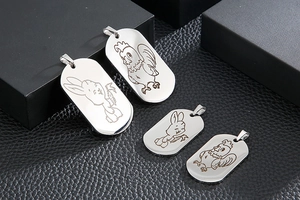 Close-up of stainless steel dog tags featuring engraved zodiac rabbit and rooster designs