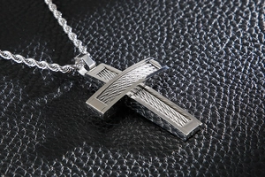 Detailed view of silver steel cross pendant with steel wire texture and twisted chain