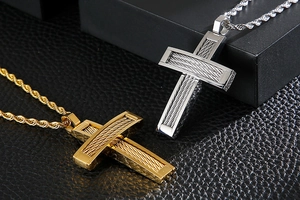 Macro shot of gold and silver cross pendants with braided steel wire on black leather