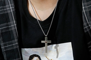 Detail of double-layered silver cross pendant with gold accent on a twisted rope chain