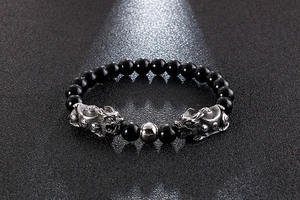 Detailed view of obsidian beads and silver Pi Xiu charms on a street style bracelet