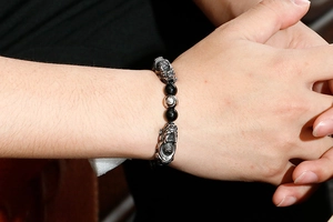 Macro detail of men's beaded bracelet featuring dual silver Pixiu charms on black beads
