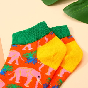 Close-up of orange cotton socks with green palm trees and pink elephant patterns