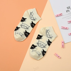 Close-up of cream low-cut cotton socks featuring cute cartoon black and white cat patterns