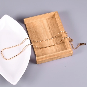 Detailed close-up of a minimalist K18 gold-plated bead necklace on a decorative tray