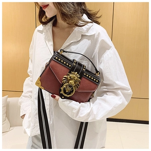 Close-up of retro crossbody bag with golden lion head emblem and striped strap