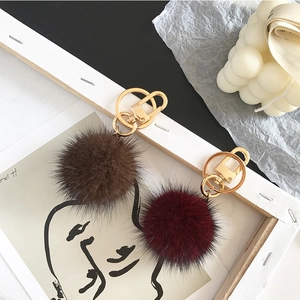 Detailed view of fluffy brown and burgundy fur pompoms with high-quality gold keychains