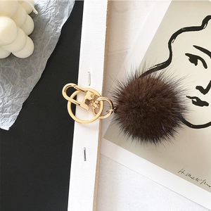 Detail of dark brown mink fur pom-pom keychain with golden metal ring and clasp