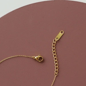 Macro shot of 14K gold-plated bracelet featuring a lobster clasp and adjustment chain
