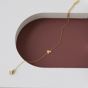 Macro detail of a 14K gold minimalist heart bracelet with lobster clasp and extension chain