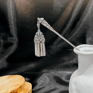 Detailed silver hairpin with hollow turquoise flowers and elegant tassels on a vase