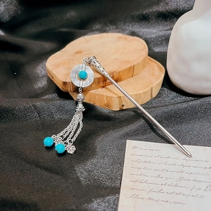 Silver Chinese hairpin with blue gemstone and tassel on vintage wood and fabric