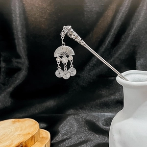 Close-up of silver hair pin with fan-shaped charm and turquoise floral tassel details