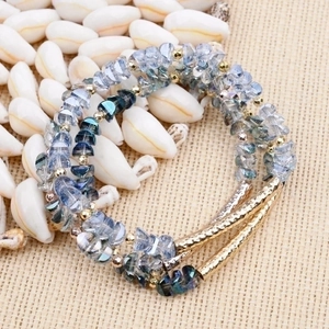 Multi-layer faceted crystal beaded bracelet with gold metal tubes on white seashells