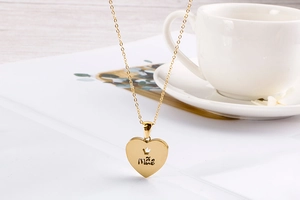 Detail of gold heart pendant with crown engraving and Mãe inscription for Mother Day