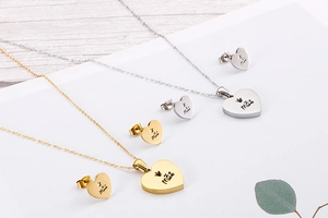 Detail of heart necklaces and earrings in gold and silver with Mãe engraving