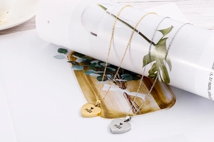Detail of heart pendants with Mãe engraving and crown symbol in gold and silver finish