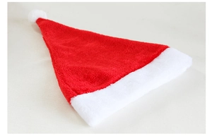 Close-up of high-quality red short plush Christmas hat with white faux fur pompom and trim