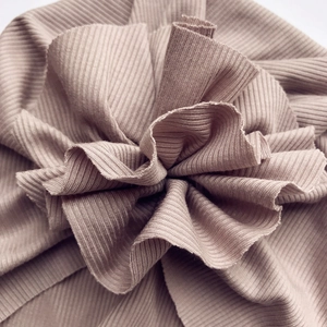 Detail of soft ribbed cotton fabric and intricate flower petal pleats on baby hat