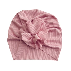 Detail showing soft pink ribbed knit baby turban hat with a large decorative fabric flower