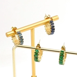 Detail view of gold C-shaped earrings with blue and green rectangular zircon stones