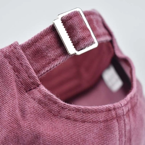Close-up of washed cotton baseball cap featuring an adjustable metal silver buckle