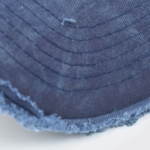 Close-up of navy cotton baseball cap brim with distressed edges and parallel stitching