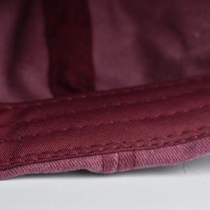 Close-up of double-stitched seams on distressed burgundy cotton vintage baseball cap