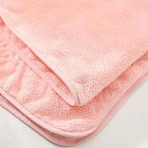 Detail of soft pink coral fleece towel showing reinforced edges and thick plush fibers