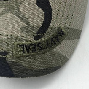 Detailed close-up of Navy Seal embroidery on camouflage canvas baseball hat fabric