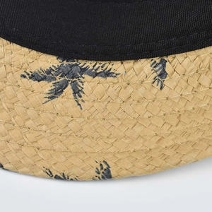 Macro detail of natural straw weave and palm leaf print on a classic fedora sun hat