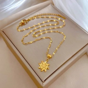 Close-up of golden sunflower pendant necklace on beige leather stand with silk background