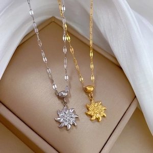 Gold and silver rotating windmill necklaces with flat link chains in a beige jewelry box