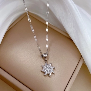 Detailed close-up of a silver windmill pendant necklace on a beige jewelry display box