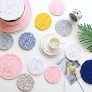 Detailed top view of various colorful woven cotton rope coasters on a white table