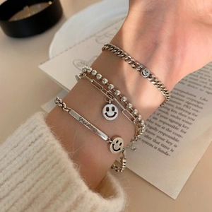 Nahaufnahme silberner mehrlagiger Armbänder mit Smile-Anhänger und SMILE-Gravur
