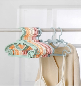 Close-up of colorful adjustable plastic baby hangers with clothes on a rod