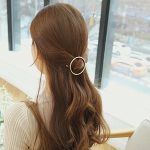 Elegant gold circular metal hair clip for women styled on hair in natural light