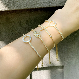Set of four adjustable gold-plated bracelets with cross, heart, and hamsa hand charms