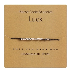 Detail view of handmade Morse code bracelet with Luck message on craft card